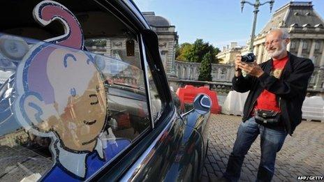 A man takes a picture of a vehicle of "Tintin magazine" car rally on September 8, 2013 in Brussels.