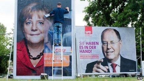 A man puts on election billboards featuring Angela Merkel and her challenger Peer Steinbrueck. Photo: 9 September 2013