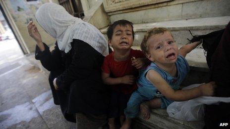 Young Syrian refugees from Aleppo beg with their mother (L) on the steps of a bank in a street in Beirut