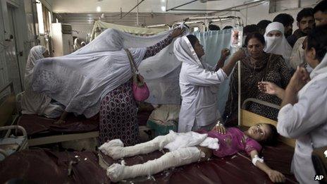 Pakistani girl who was injured in a suicide attack on a church lies in a hospital bed surrounded by relatives and nurses