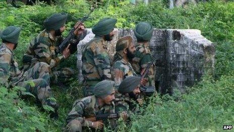 Indian army soldiers gather behind a wall during an attack by militants on an army camp at Mesar, Kashmir. Photo: 26 September 2013