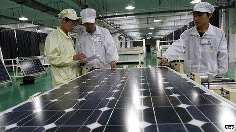 Workers inspect a solar panel in a Chinese factory