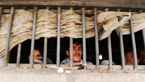 Afghan prisoners look on through bars during a visit by local and international media at Pul-e Charkhi prison on the outskirts of Kabul on March 7, 2010