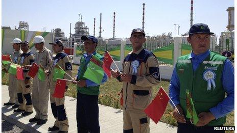 Workers hold Chinese and Turkmenistan state flags as they attend a launching ceremony at Galkynysh gas field in eastern Turkmenistan (4 September 2013)