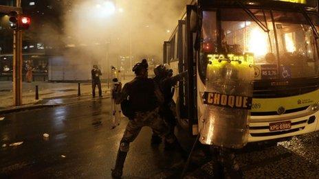 Riot policemen try to extinguish a fire in a bus after demonstrators set fire to it during a protest in Rio de Janeiro on 7 October 2013.