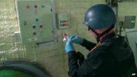 This image made from video broadcast on Syrian State Television on 8 October purports to show a chemical weapons expert taking samples at a chemical weapons plant at an unknown location in Syria