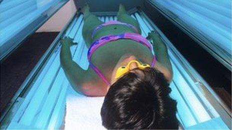 Person tanning in a sunbed unit
