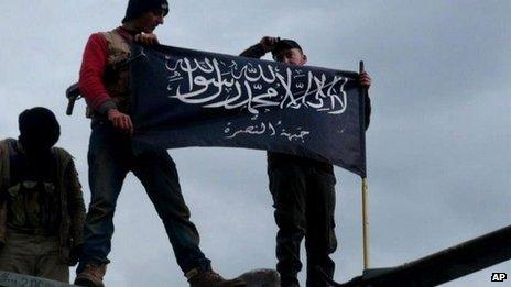 Members of the al-Nusra Front raise its banner above a military base in Idlib province (11 January 2013)