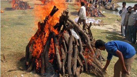 An unidentified person performs the last rites during a mass cremation of the women and children who died during a stampede in Lucknow, India, 13 April, 2004