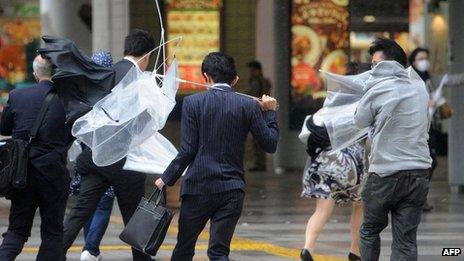 People walk against strong wind and rain in Tokyo on 16 October 2013