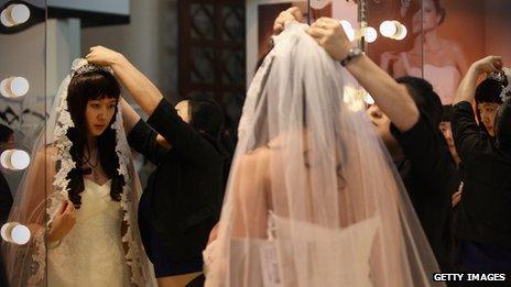 A Chinese woman tries on a wedding dress at the 2012 China Spring Wedding Expo at Beijing Exhibition Center (file photo)