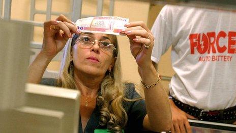 Cuban cashier inspects a Cuban convertible peso note at a supermarket in Havana on 10 November 2004