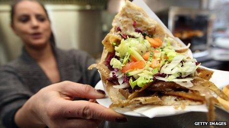 An employee of a doner kebab stand serves a doner sandwich in Berlin, Germany (23 February 2013)