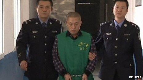 Journalist Chen Yongzhou, in handcuffs, is escorted by police officers at the Changsha Public Security Bureau detention centre in China