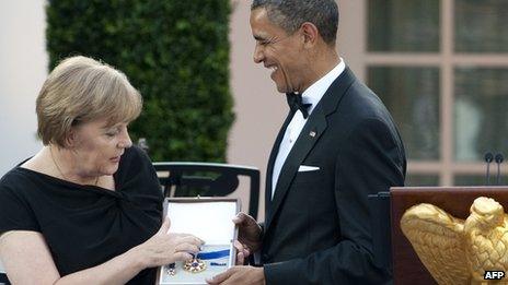 US President Barack Obama presents German Chancellor Angela Merkel with the 2010 Presidential Medal of Freedom during a State Dinner in the Rose Garden at the White House in Washington (7 June 2011)