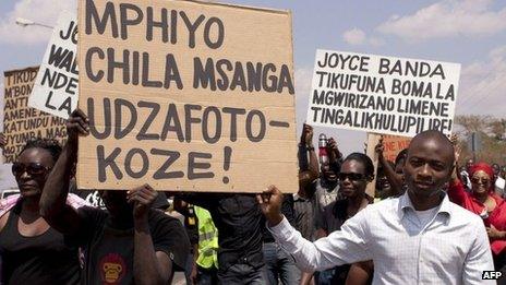 Protesters in Malawi hold up placards wishing Malawi's Budget Director Paul Mphwiyo a quick recovery, so that he can come home soon from South Africa where he is receiving treatment following his attempted assassination - October 2013