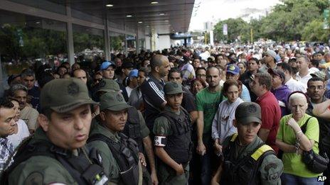 National Guard Soldiers stand on guard as shoppers wait outside an electronics store in Caracas on 9 November, 2013