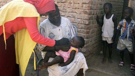 A social worker (L) gives a polio drop to a child from al-Muniera village in Madani, the capital of al-Jazirah state in east-central Sudan (18 November 2007)
