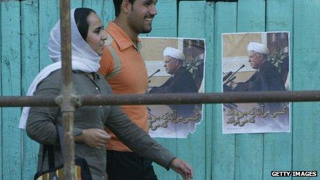 Iranians walking past campaign posters