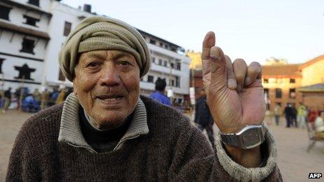 A Nepalese man shows his finger after an election official marked it with indelible ink at a polling station in Kathmandu on 19 November 2013