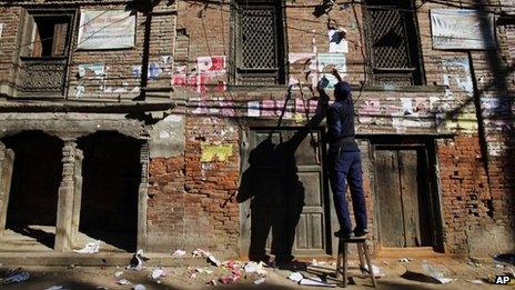 A Nepalese policeman removes election campaign posters from a wall near a polling booth in Bhaktapur, Nepal, 18 November 2013
