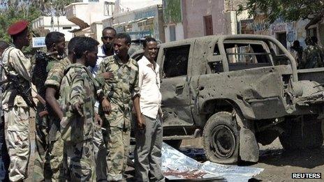 Somali policemen stand next to a damaged car at the scene of an explosion in Beledweyne in central Somalia, 19 November 2013