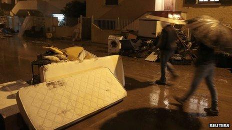 People walk in a flooded street in Olbia, north-eastern Sardinia
