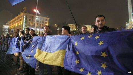Activists wave Ukrainian and European Union flags during a night rally in support of Ukraine's integration with the European Union in Kiev