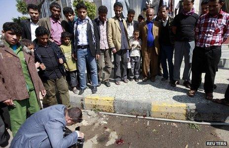 A man takes a photograph of the scene of the shooting in Sanaa (26 November 2013)
