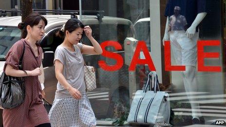 Women walk past a sale sign in Japan