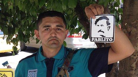 A street vendor holds up a sticker with an image of Pablo Escobar