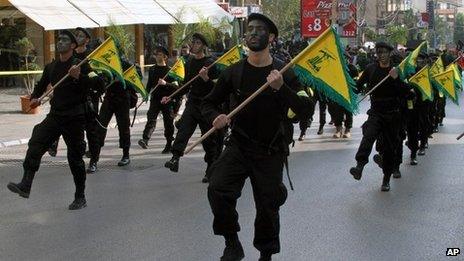 Hezbollah fighters hold their party flags, as they parade during a rally to mark the 13th day of Ashoura