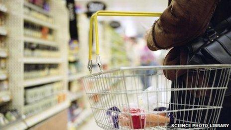 Woman in a supermarket holding a shopping basket.