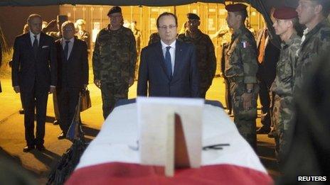 French President Francois Hollande pays tribute near a flag-draped coffin bearing one of two French soldiers killed in Bangui