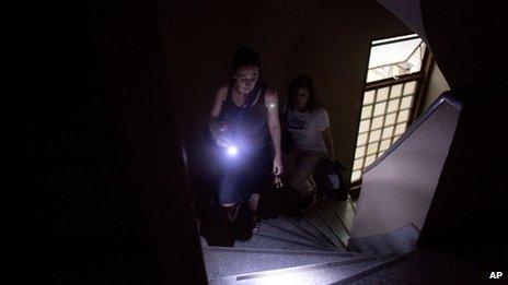 Using her cell phone as a flash light, a woman walks up the stairs to her sixth floor apartment in a building that has been without electricity for two weeks in Buenos Aires on 26 December, 2013