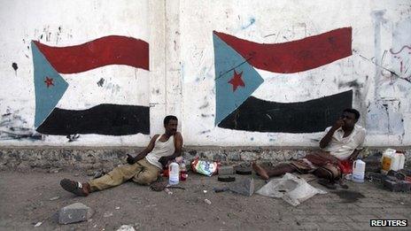 Men sit beside painted flags of the former South Yemen in Aden (August 2013)