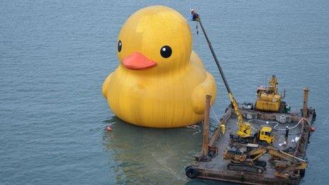 Cleaners scrub a giant yellow duck at Keelung port in New Taipei City, Taiwan, 28th December