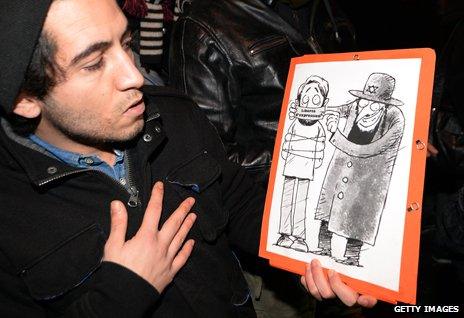 A Dieudonne supporter displays an anti-Jewish cartoon