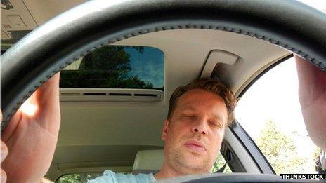 A man asleep at the wheel of a car