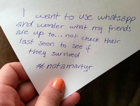 A hand holding a note which reads: "I want to use whatsapp and wonder what my friends are up to... not check their last seen to see if they survived #notamartyr"