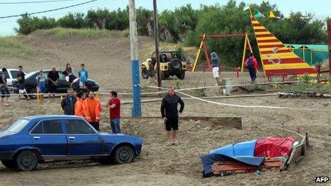People remain near a corpse after a lightning killed three tourists in Villa Gesell, Argentina on January 9, 2014