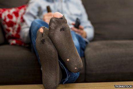 man with feet up on table and holes in socks