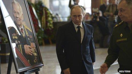 Russian President Vladimir Putin walks past a portrait of Mikhail Kalashnikov during a memorial ceremony outside Moscow, December 27, 2013
