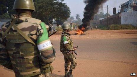 Congolese soldiers from the African-led International Support Mission to the Central African Republic (MISCA) stand guard in a street where people burnt tyres following the killing of a man by an ex-Seleka member, on 12 January 2014, in Bangui