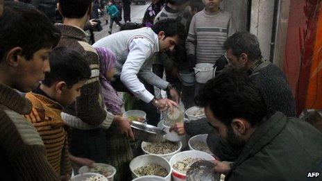 Syrian youths gather to receive aid food in the northern Syrian city of Aleppo