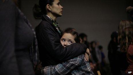 Nine-year-old Raelynn Holloway, hugs her mother Rhiannon Holloway, left, during a prayer vigil for the victims of the Berrendo Middle School shooting in Roswell, New Mexico 14 January 2014