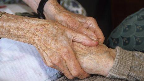 Carer holding elderly person's hands