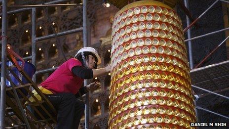 A roped climber removes Buddha statues from a tall column at the Fo Guang Shan temple in Kaohsiung