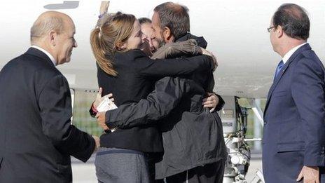 Former French hostage Daniel Larribe is welcomed by relatives as President Francois Hollande (far right) and Defence MInister Jean-Yves Le Drian look on