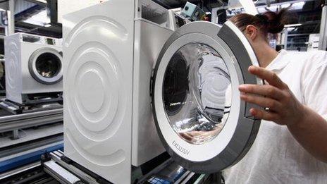 A factory worker assembles a washing machine